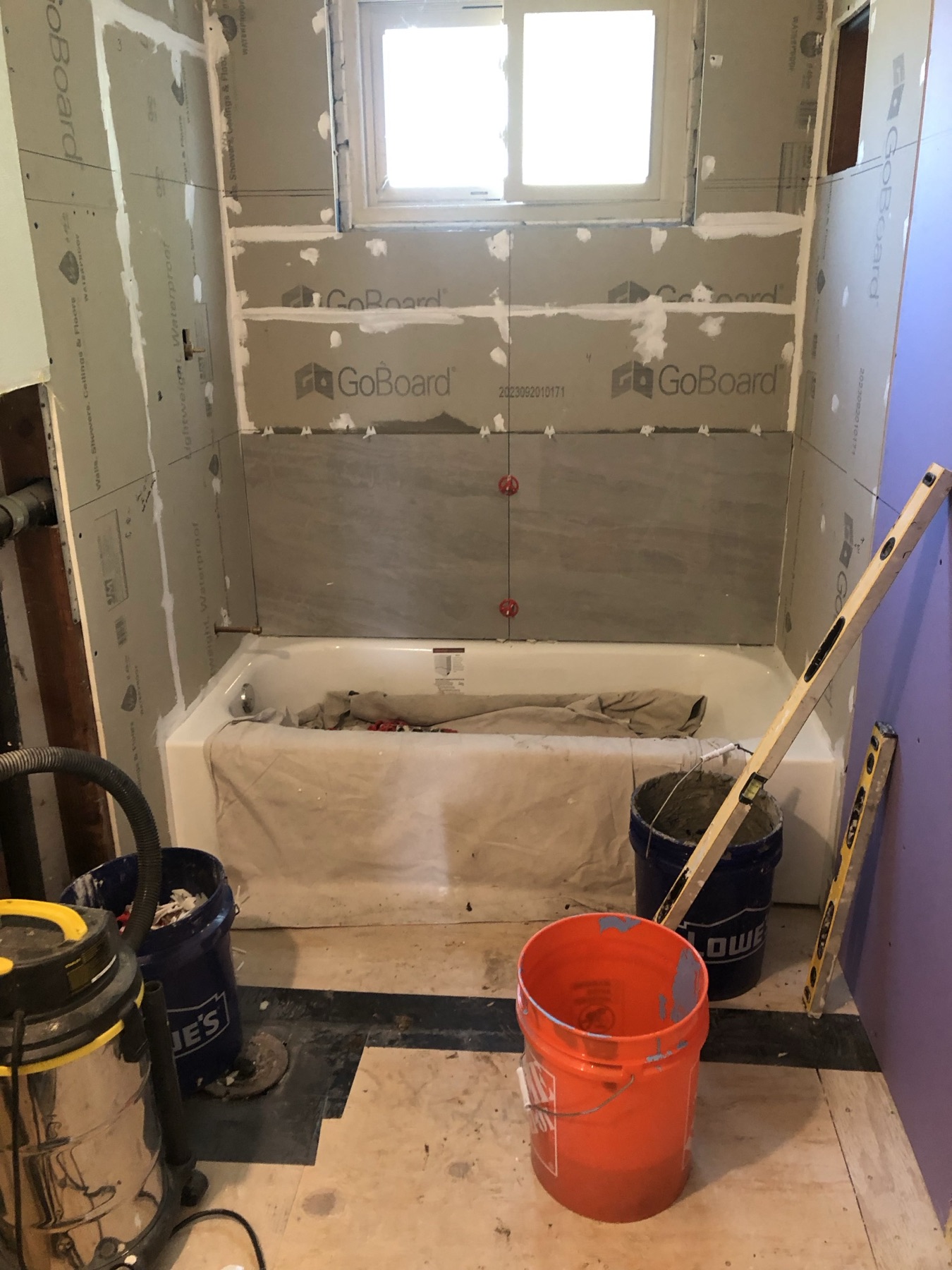 Cement backer board installed around a bathtub and window, ready for tile