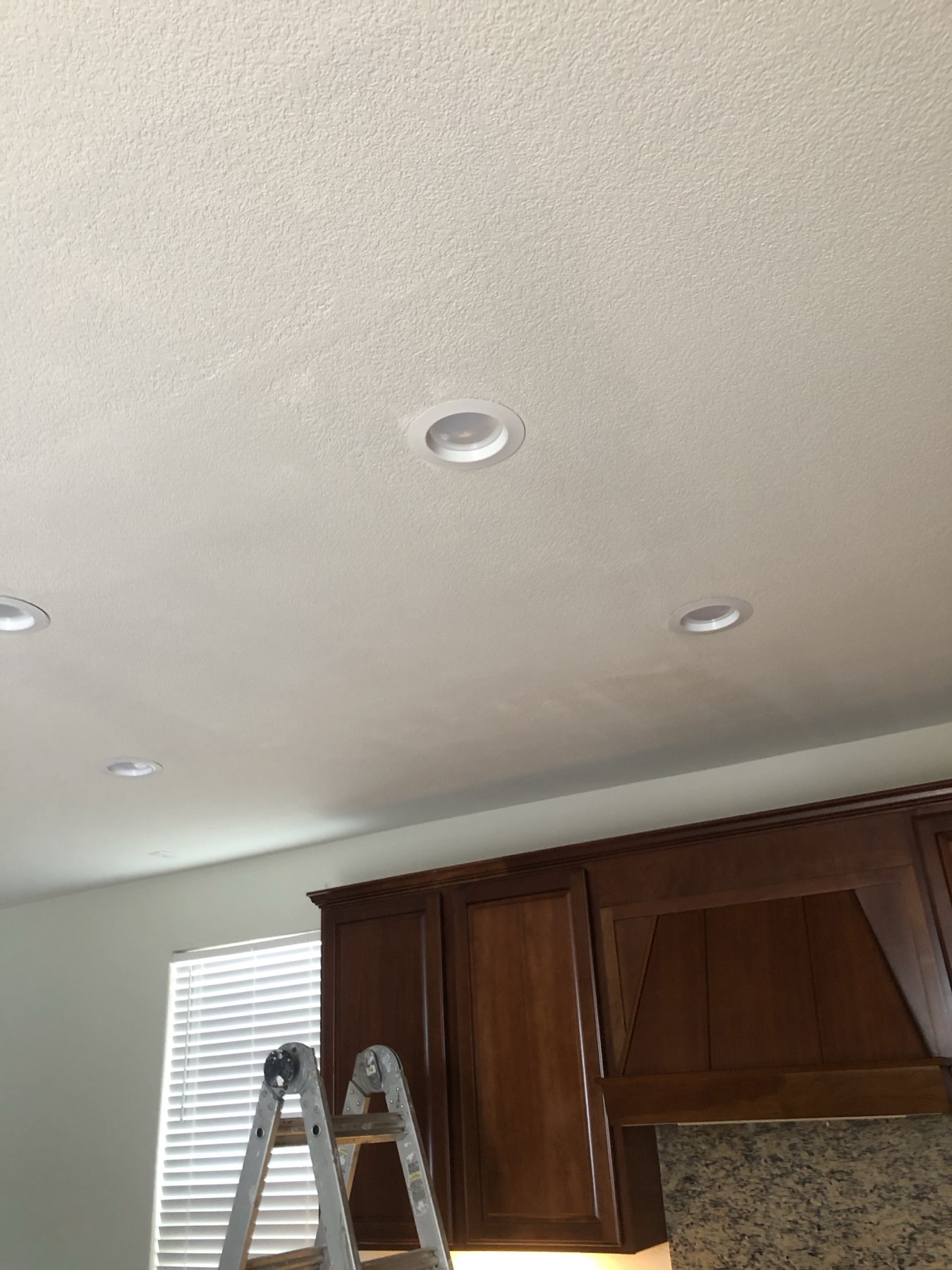 Finished kitchen ceiling after the drywall repair, with the ladder still in place