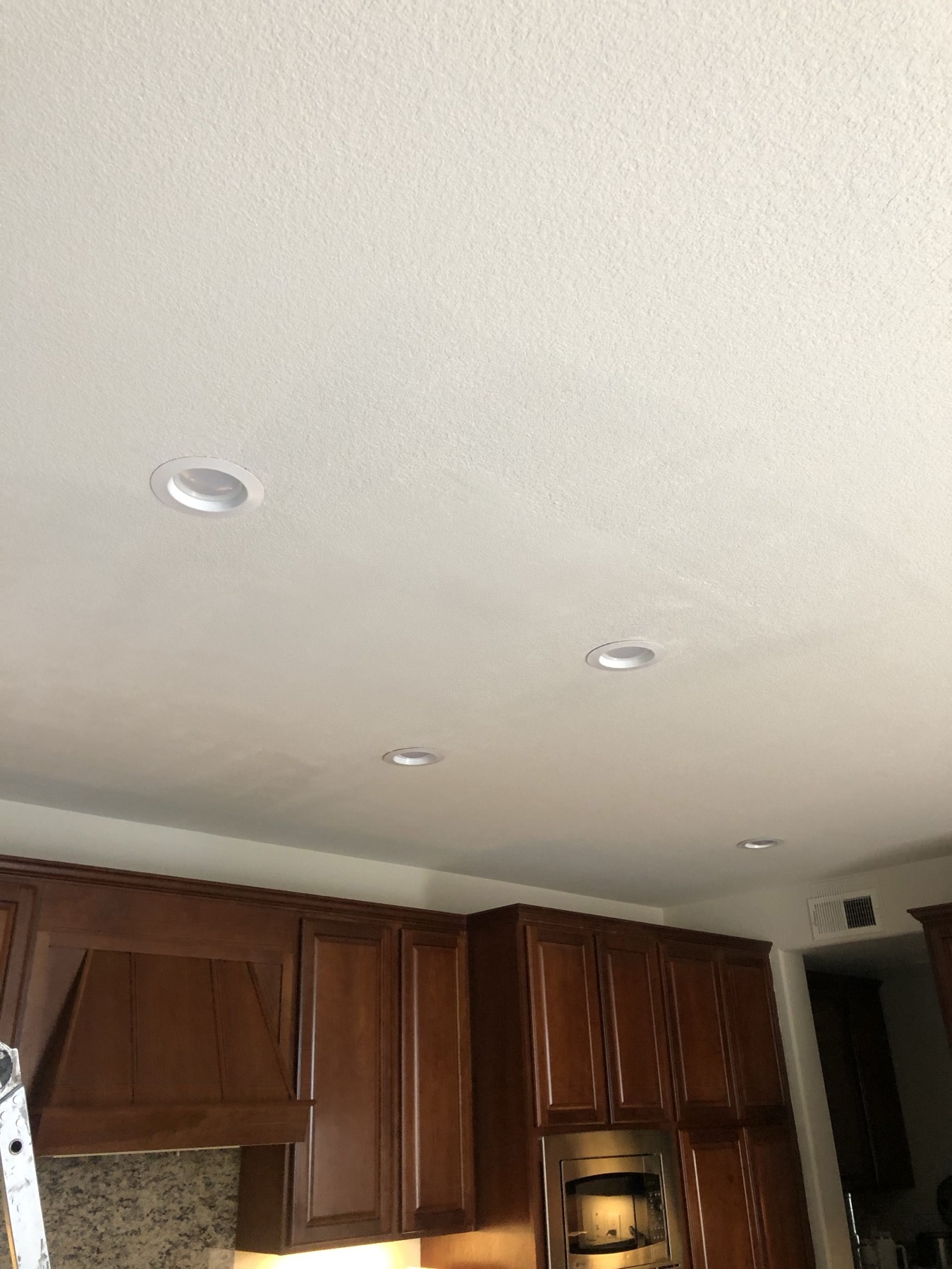 Repaired kitchen ceiling with smooth, matching texture above wood cabinets