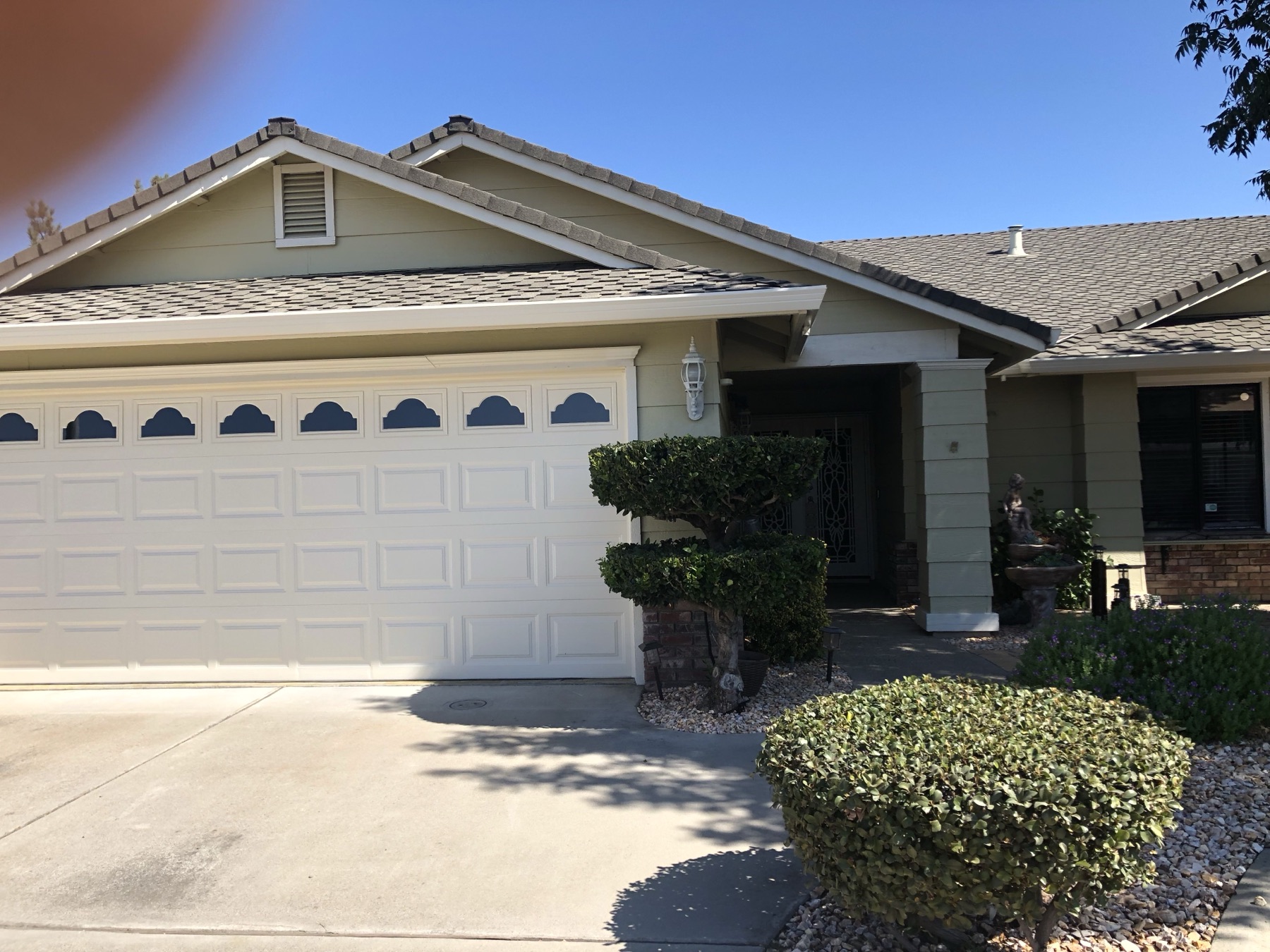 Repainted sage green home with cream trim and a white garage door