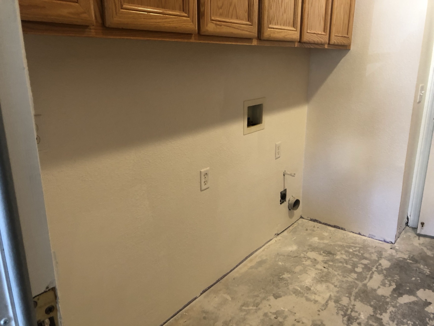 Finished laundry room wall, smooth and even below the oak cabinets