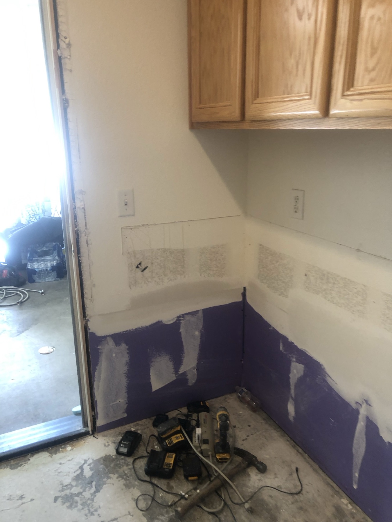 New purple moisture-resistant drywall along the bottom of a laundry room wall