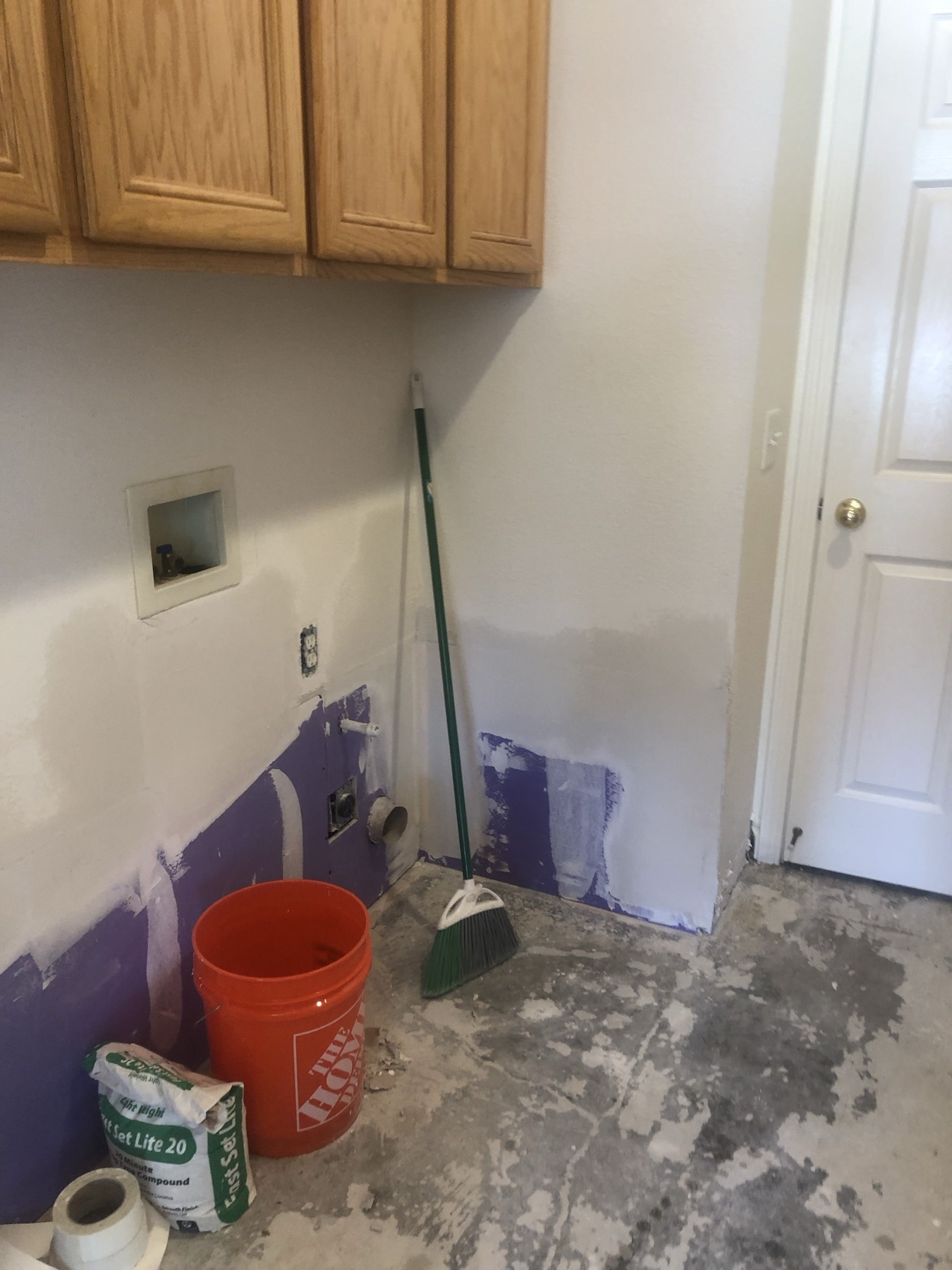 Taped and mudded drywall seams in a laundry room below oak cabinets